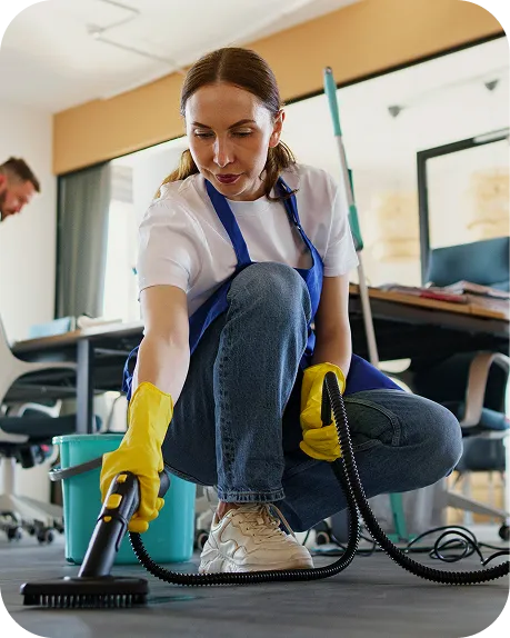 Profissional de limpeza com luvas aspirando o piso de um escritório